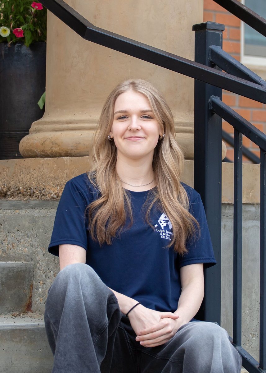 Alayna, Hodder Sparkle & Shine cleaner, sitting on steps in her HSS t-shirt