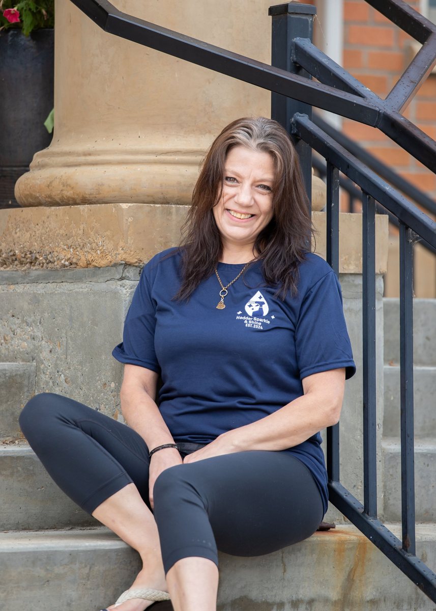 Roxanne, Hodder Sparkle & Shine cleaner, smiling on steps in her HSS t-shirt